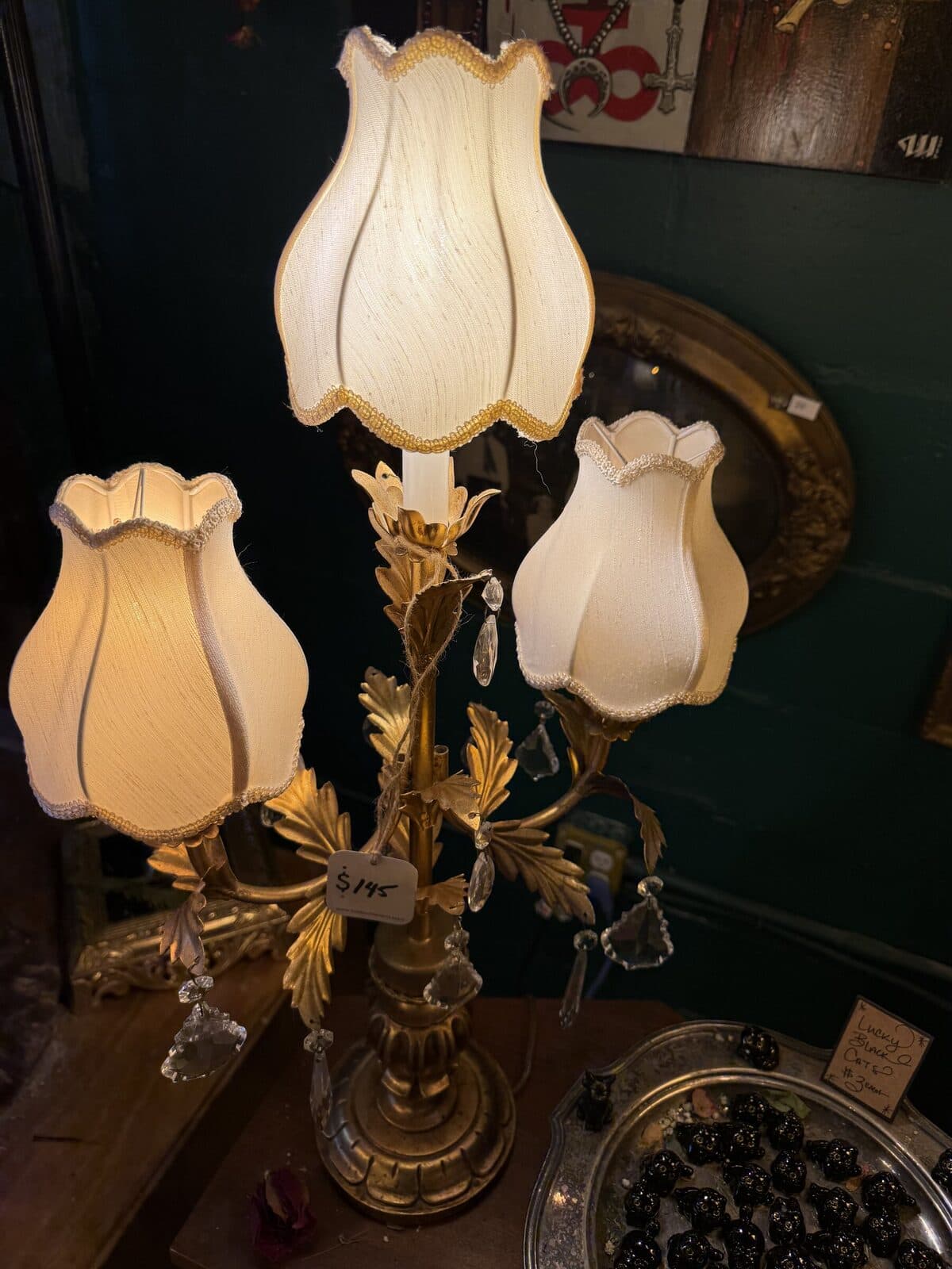 A pair of cream-shaded sconce lamps with crystal drops, glowing warm against teal walls.